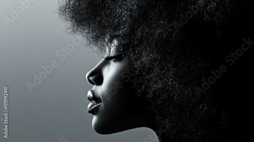 Profile of a young Black woman with a large afro hairstyle, in monochrome.
