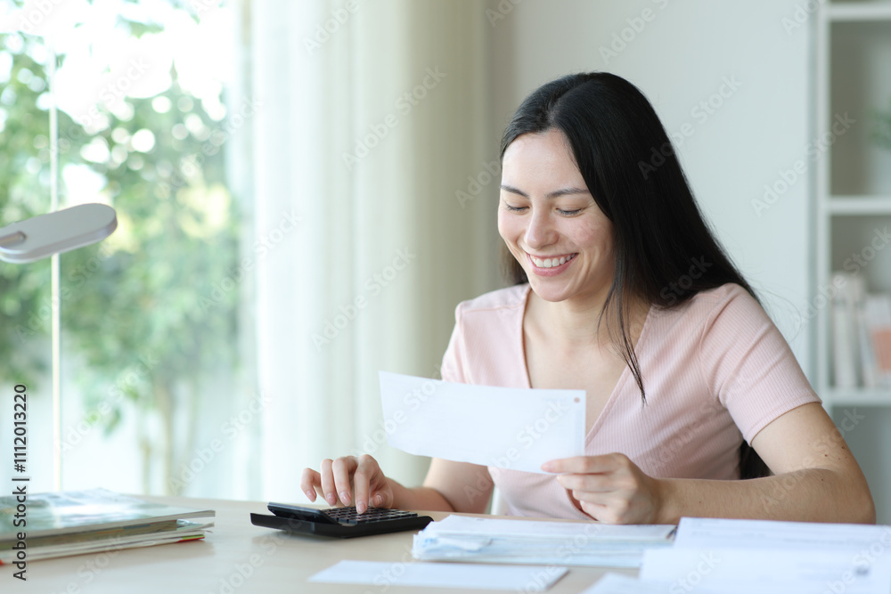Happy asian woman calculating invoices at home Happy asian woman calculating invoices at home