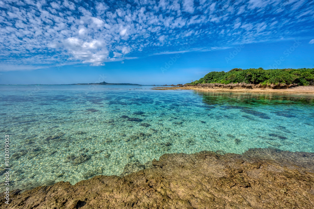 Crystal clear waters of Bise Beach, Motobu District, Okinawa main island. White sand beach with coral outcrops and small islands offshore. Crystal clear waters of Bise Beach, Motobu District, Okinawa main island. White sand beach with coral outcrops and small islands offshore.