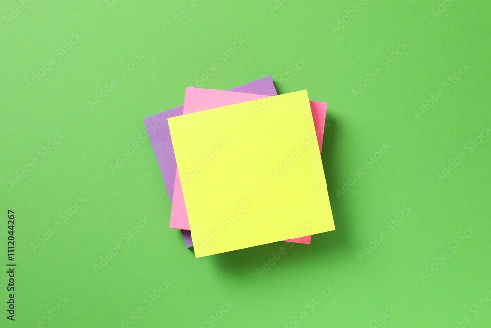 Top view of stack of colorful sticky notes on green background Top view of stack of colorful sticky notes on green background