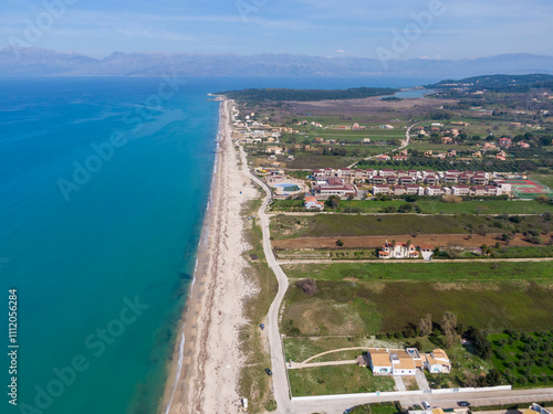 Aerial view of a coastal area with green fields, resorts, and a sandy beach meeting turquoise waters. photo