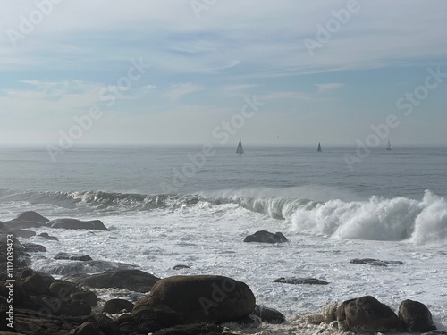 Atlantic Ocean seascape with crashing waves and sailboats near Canidelo, Vila Nova de Gaia, Porto, Portugal, January 2024