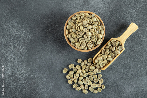 A wooden bowl filled with green coffee beans, top view