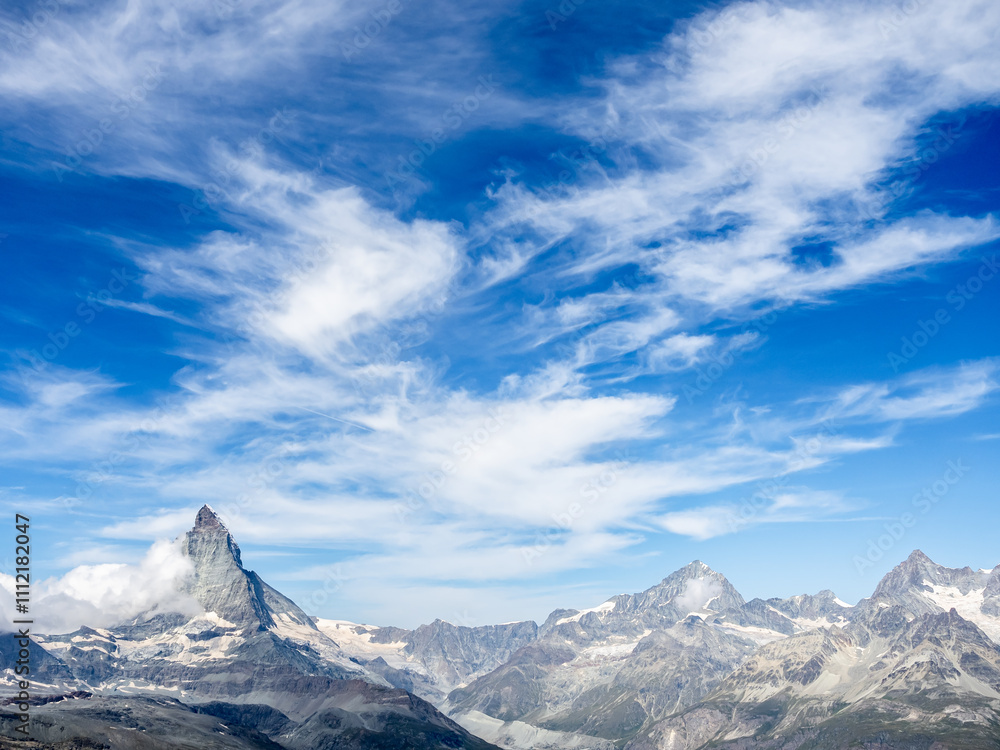 Panoramic scene of Matterhorn peak and many peaks Swiss Alps. Amazing view of Matterhorn on bright blue sky and cloud background. Tourist destination with mountains at Switzerland in summer. Panoramic scene of Matterhorn peak and many peaks Swiss Alps. Amazing view of Matterhorn on bright blue sky and cloud background. Tourist destination with mountains at Switzerland in summer.