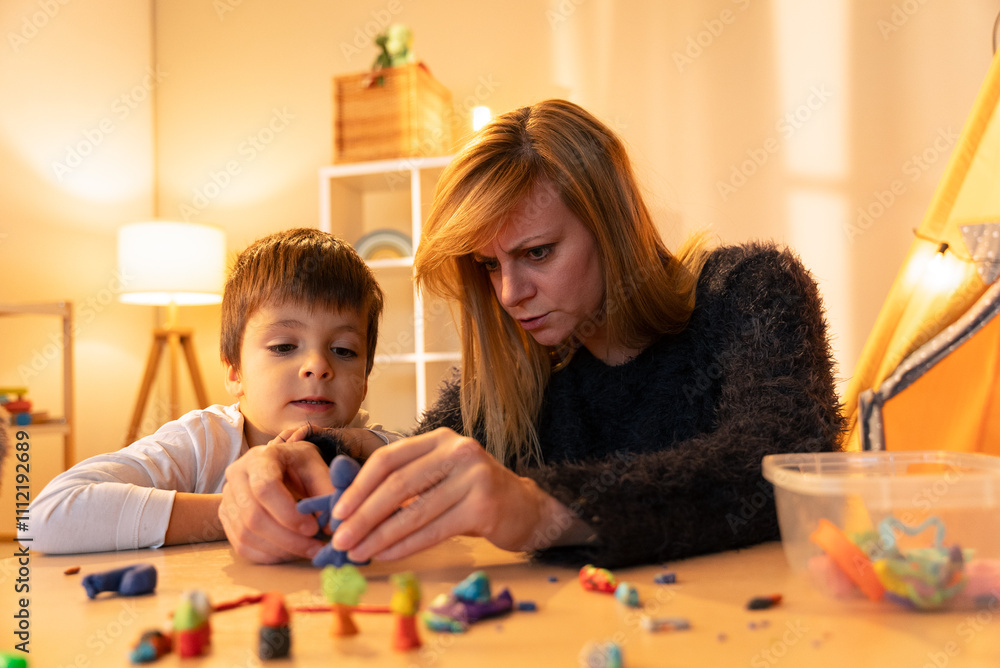 Fototapeta premium Childminder and boy playing with modeling clay at home