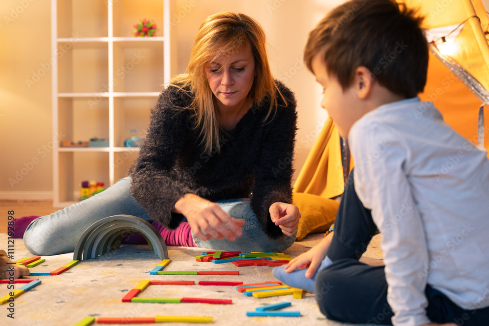 Fototapeta premium Child psychologist playing with colorful wooden blocks with a child in the playroom