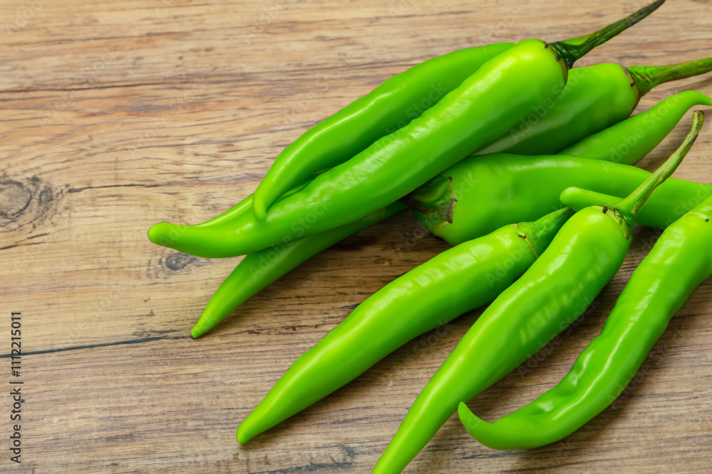 Green chili peppers on a wooden table. A wooden background with green peppers. Green pepper wooden background hot pod lies on. A wooden pod lies on the background of a hot lifestyle pepper. Green chili peppers on a wooden table. A wooden background with green peppers. Green pepper wooden background hot pod lies on. A wooden pod lies on the background of a hot lifestyle pepper.