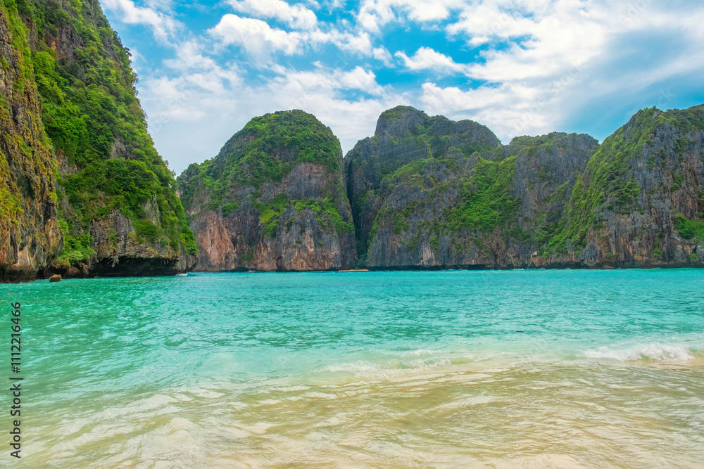 Obraz premium Maya Bay tropical sandy beach with turquoise water ocean on Phi Phi islands, Krabi, Thailand with nobody. Empty beach, surrounded by towering green cliffs under bright blue sky