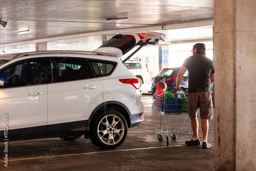 dad pushing trolley in undercover carpark with toddler girl