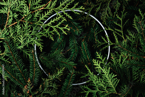 Christmas mockup with pine branches and a metallic ring on a dark background creating a festive and cozy atmosphere