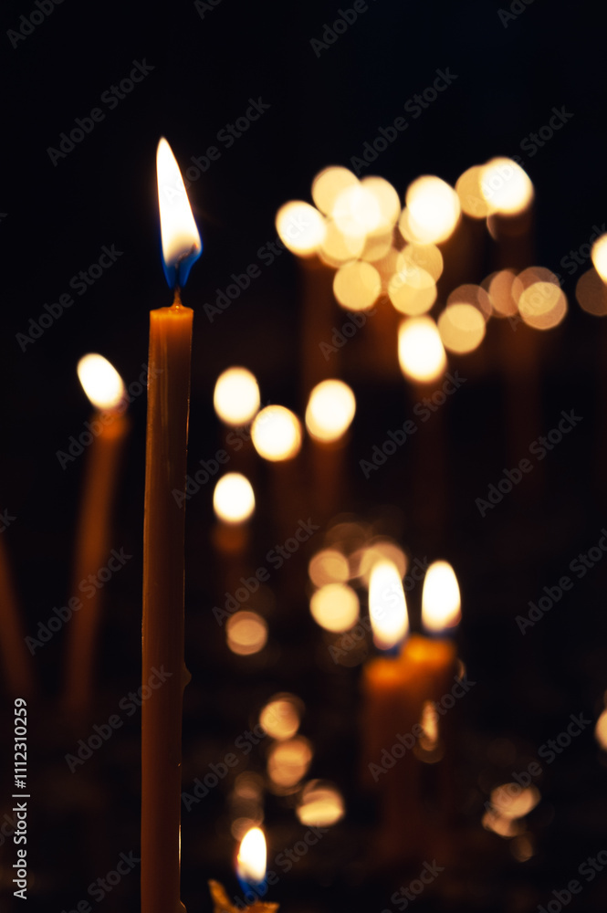 Soft bokeh lights surround the burning candle, creating a spiritual atmosphere Soft bokeh lights surround the burning candle, creating a spiritual atmosphere