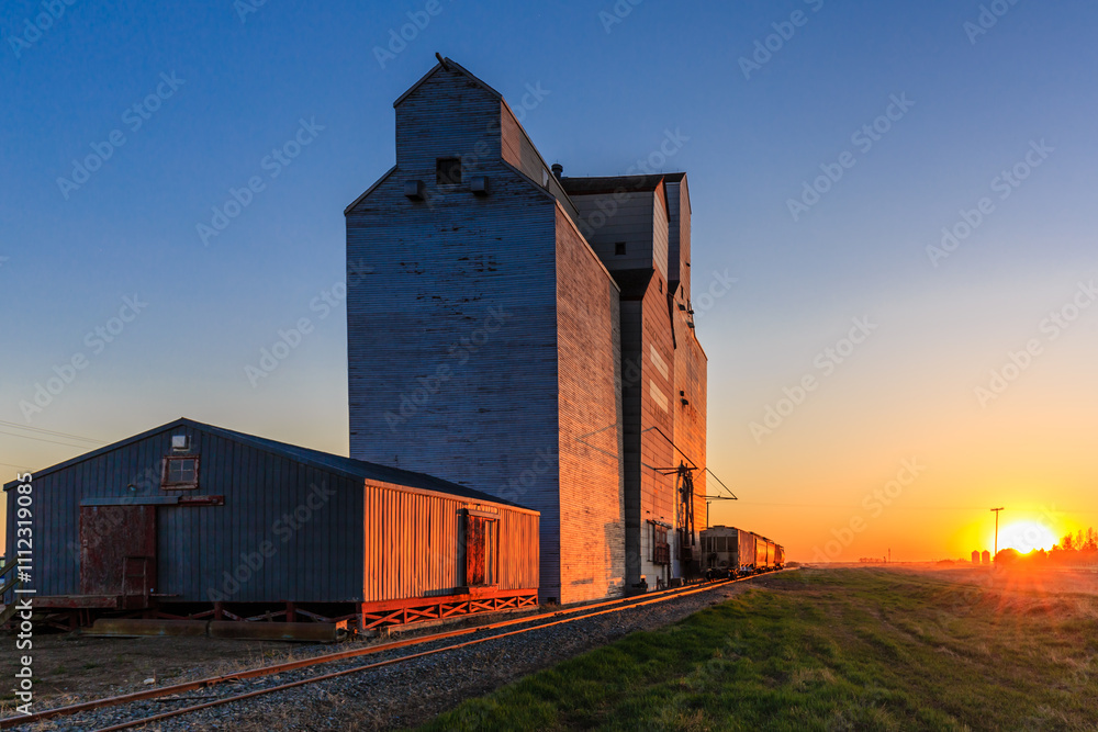 Fototapeta premium A train is pulling a large grain silo
