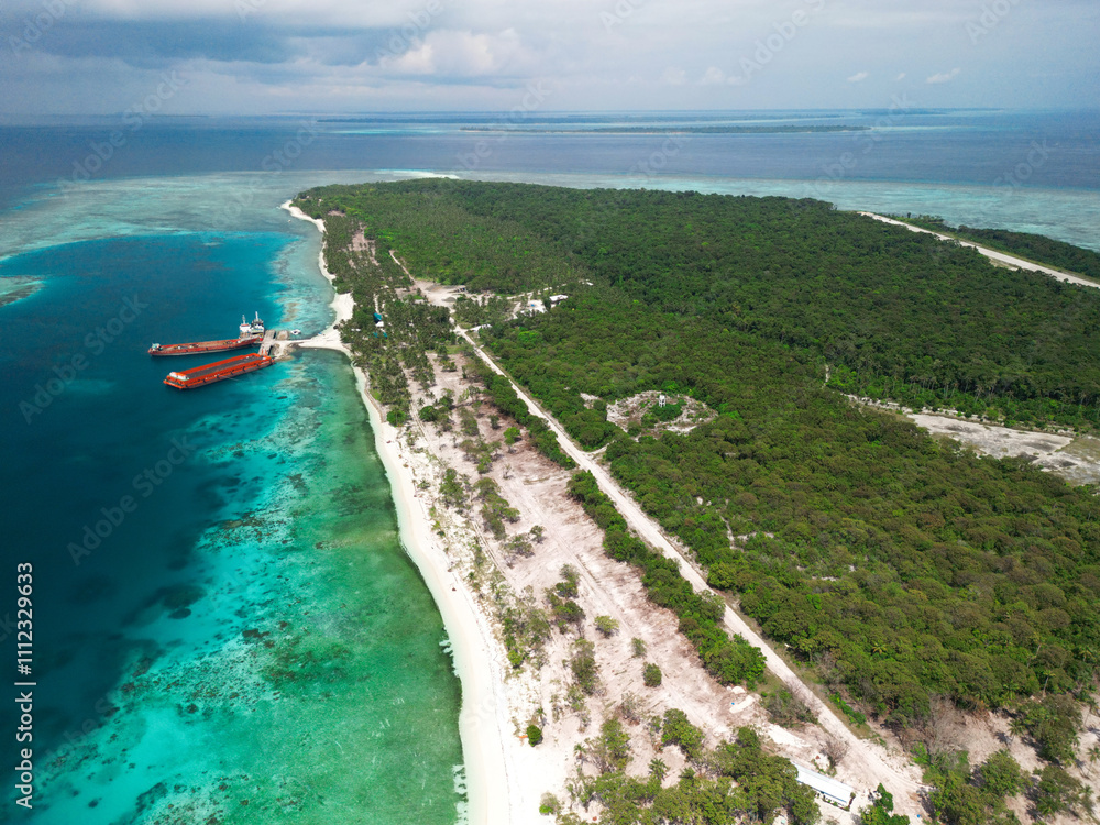 An aerial view of Starfish Island in Balabac, Philippines, showcasing lush greenery, a sandy coastline, turquoise waters, and docked barges An aerial view of Starfish Island in Balabac, Philippines, showcasing lush greenery, a sandy coastline, turquoise waters, and docked barges