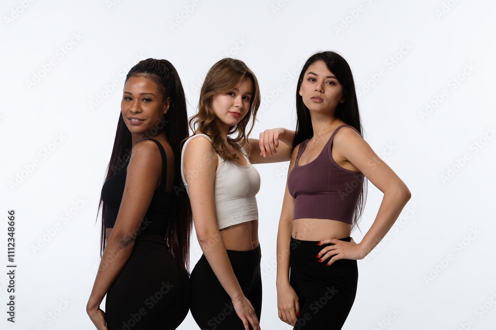 Three positive multiracial young women posing at camera looking smiling, isolated on white studio background. Multicultural beauty concept. Three positive multiracial young women posing at camera looking smiling, isolated on white studio background. Multicultural beauty concept.