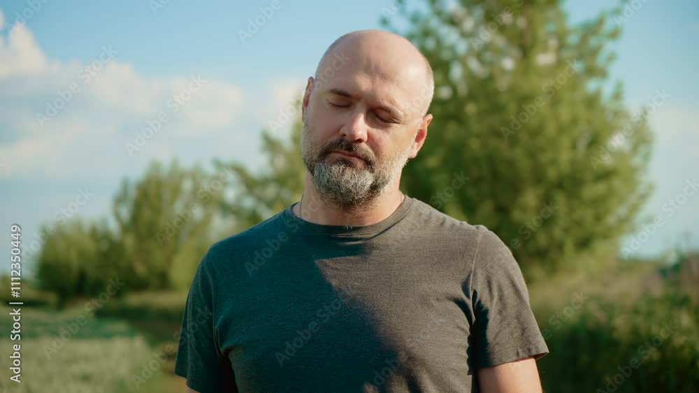 Relaxed male stretching neck outdoors to release tension and improve flexibility. Calm man focusing on gentle neck movements to relieve stress and enhance relaxation. Mindful guy practicing neck Relaxed male stretching neck outdoors to release tension and improve flexibility. Calm man focusing on gentle neck movements to relieve stress and enhance relaxation. Mindful guy practicing neck