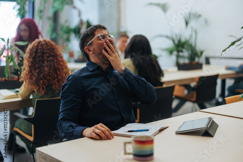 Tired office worker yawning during business meeting
