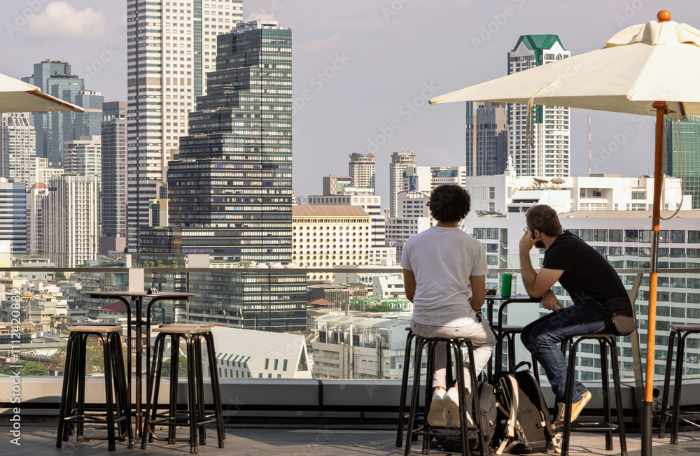 wo men tourists while relaxing looking at Modern skyscrapers of Bangkok city.