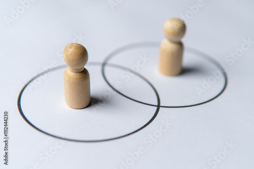 Two wooden figures standing in separate circles overlaps with each other. Consensus and agreement concept.