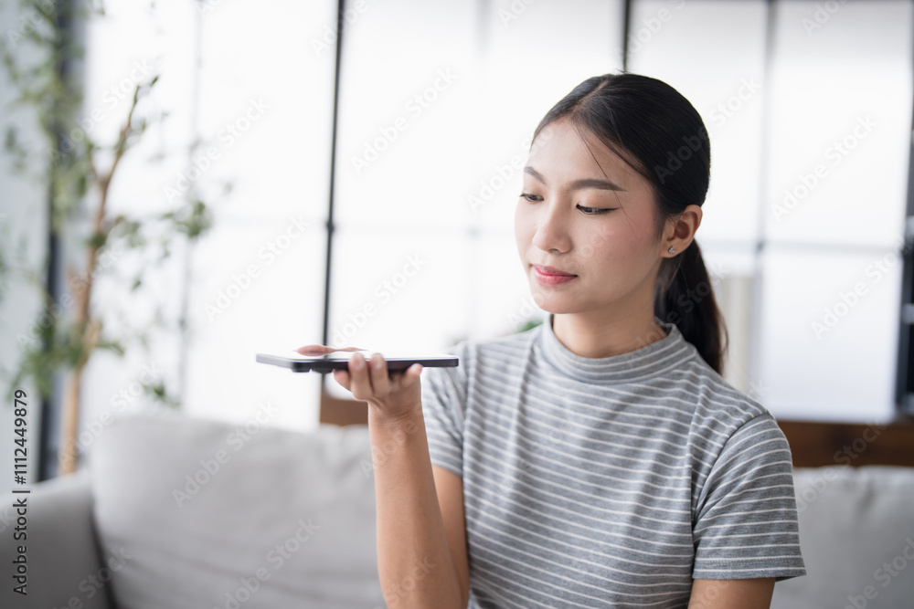 Asian woman using voice assistant on smartphone at home conversation with online assistant Voice chat bot conversational AI Modern Technologies. Asian woman using voice assistant on smartphone at home conversation with online assistant Voice chat bot conversational AI Modern Technologies.