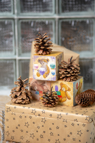 Charming Christmas arrangement featuring hand-painted wooden blocks with teddy bear illustrations, pinecones, and a star-patterned wrapped gift box. A cozy and nostalgic holiday setup, perfect for fes