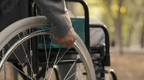Man in wheelchair moving forward in a park