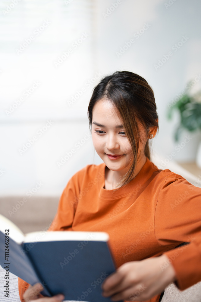 girl enjoying an interesting novel reading in living room . Hobbies and activities. Happy young asian woman reading book, sitting on sofa lady enjoying interesting story, studying for exam, girl enjoying an interesting novel reading in living room . Hobbies and activities. Happy young asian woman reading book, sitting on sofa lady enjoying interesting story, studying for exam,