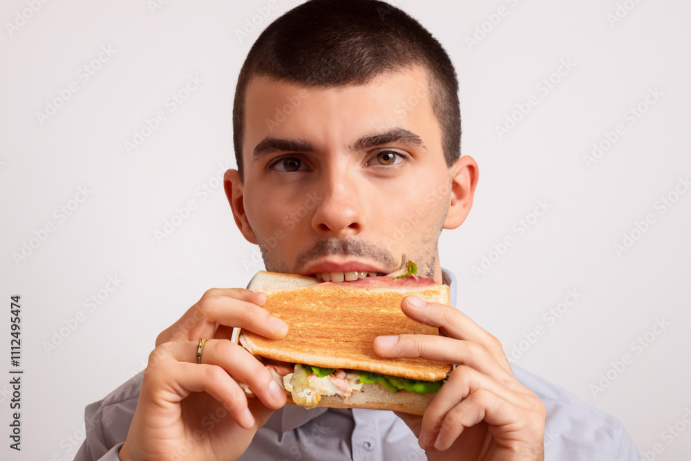 A man is holding a sandwich with meat and vegetables. A guy is preparing a sandwich on a white background. Guy sandwich white background fast food eating gray. A guy is eating a fast food lifestyle. A man is holding a sandwich with meat and vegetables. A guy is preparing a sandwich on a white background. Guy sandwich white background fast food eating gray. A guy is eating a fast food lifestyle.