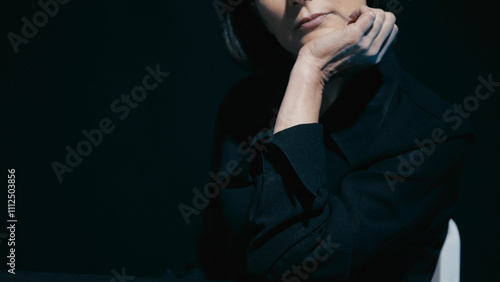 Bild auf Leinwand Flirty, self-confident woman sits in the dark room, leaning her head on her hand