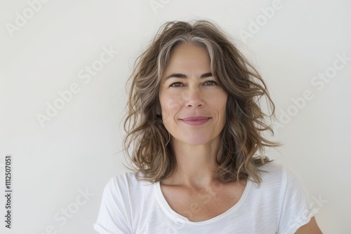 Portrait of a content woman in her 50s dressed in a casual t-shirt over white background