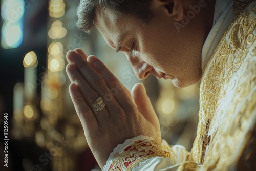 A man in priestly attire is kneeling and praying, possibly in a place of worship photo