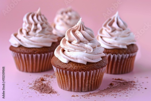 Three decorated cupcakes on a pink surface