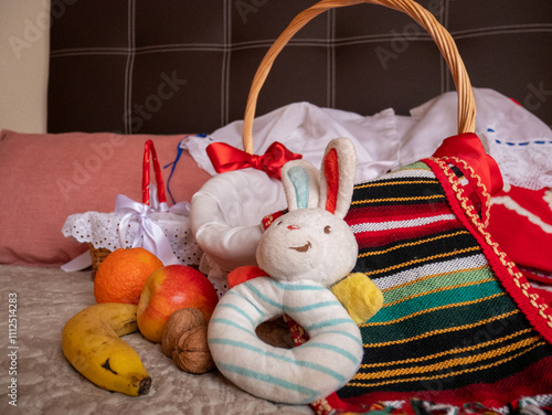 Traje tradicional infantil del sur de España en color rojo y bordado a mano con cesta de mimbre, fruta y juguete de conejo photo