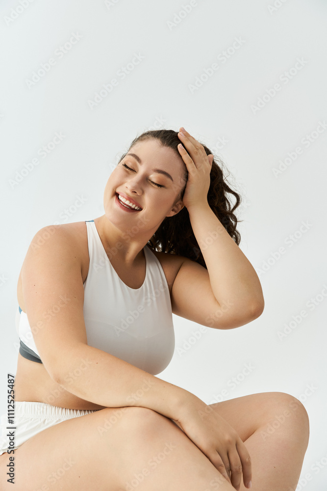 Fototapeta premium Young plus size woman embraces her beauty while posing cheerfully in trendy underwear.