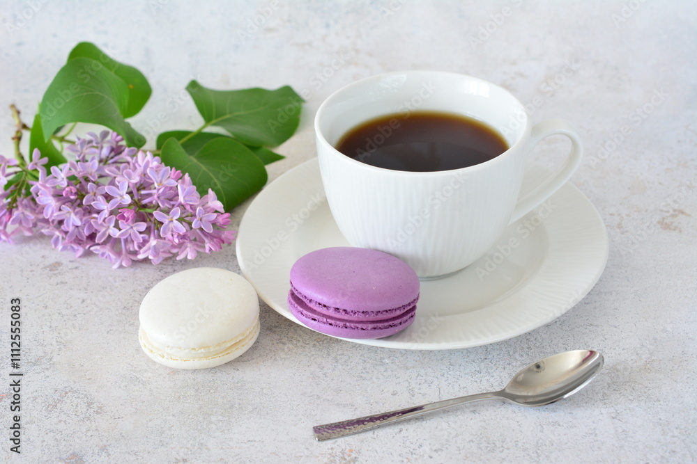 a cup of coffee next to a lilac branch and purple and white macaroons a cup of coffee next to a lilac branch and purple and white macaroons
