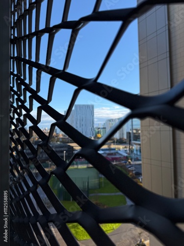Canvas Print Looking through the metal fence onto city views and modern buildings