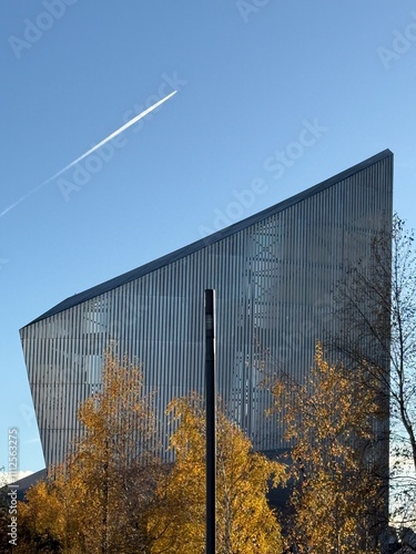 Photography Modern building with trees in the front and a clear blue sky background