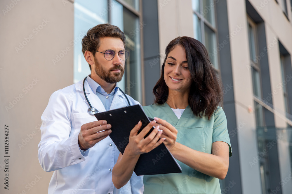 Two doctors discussing something and looking involved Two doctors discussing something and looking involved