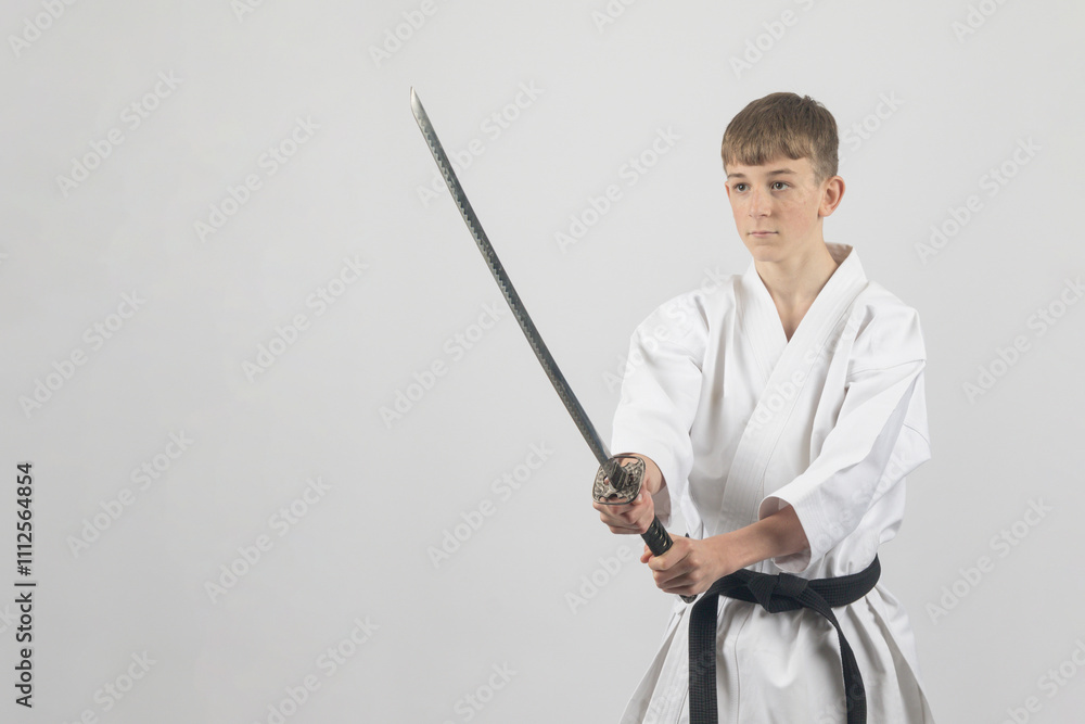 Fifteen year old male teenage karate black belt using a katana, studio shot against a white background Fifteen year old male teenage karate black belt using a katana, studio shot against a white background