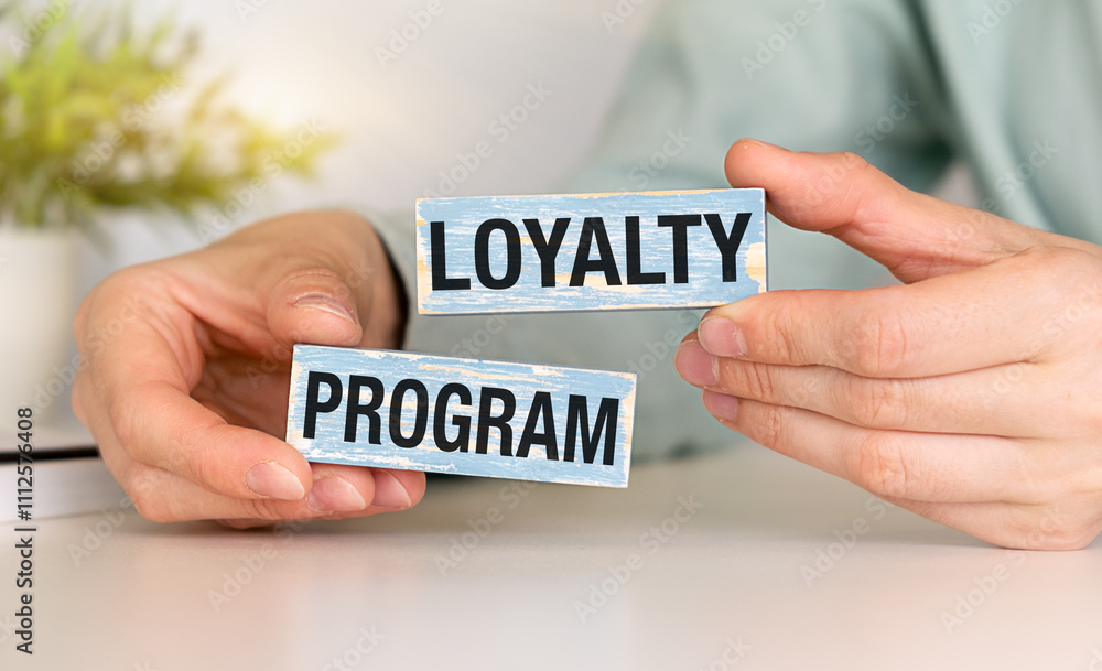 Loyalty program text on wooden blocks and on gray table with hands. Loyalty program text on wooden blocks and on gray table with hands.