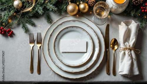 Top view of table top tablescape with festive Christmas dishes plates formal place setting cutlery gold silver crystal glasses holiday decor name card 