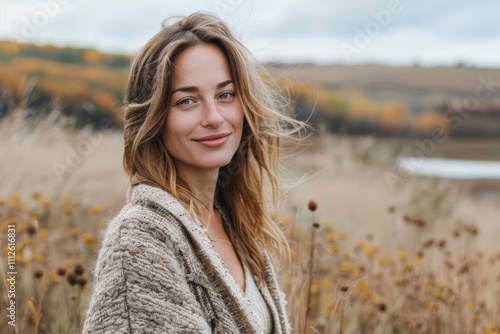 Portrait of a satisfied woman in her 30s wearing a chic cardigan while standing against quiet countryside landscape