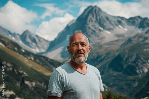 Portrait of a blissful man in his 50s dressed in a casual t-shirt over backdrop of mountain peaks