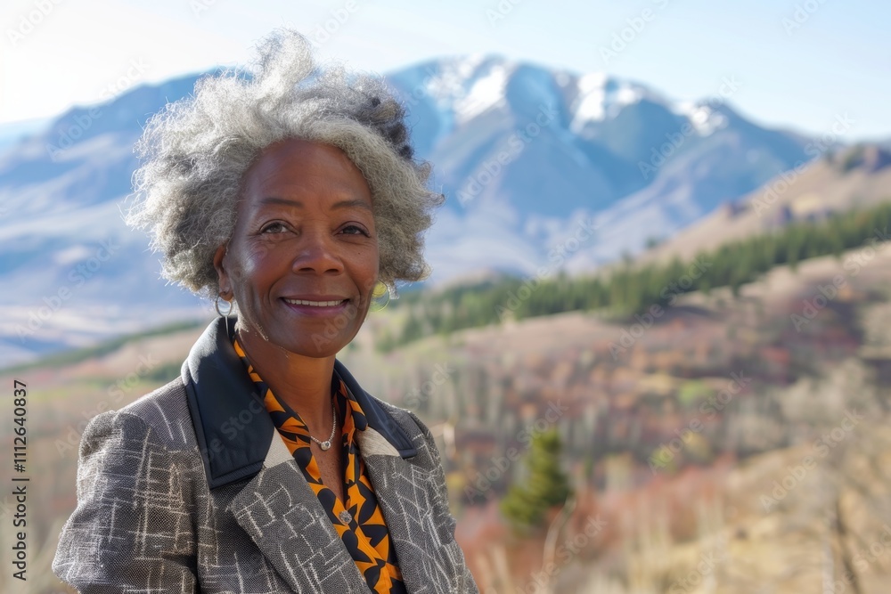 Portrait of a cheerful afro-american woman in her 60s dressed in a stylish blazer in front of backdrop of mountain peaks Portrait of a cheerful afro-american woman in her 60s dressed in a stylish blazer in front of backdrop of mountain peaks