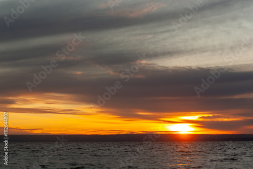 a sunset over a body of water with a few waves.