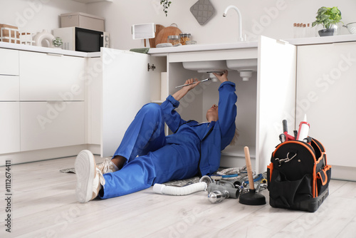 Obraz na płótnie Mature female plumber installing sink in kitchen