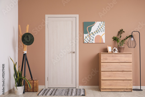 Interior of hall with stylish painting, drawers and door photo