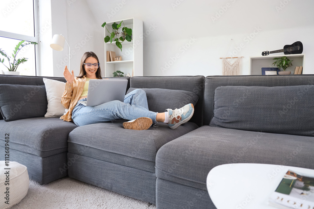 Young woman with laptop video chatting on sofa at home Young woman with laptop video chatting on sofa at home