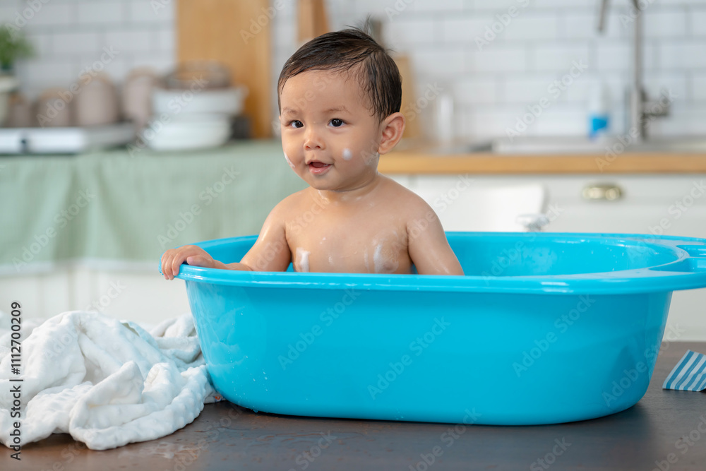 Asian baby taking a bath in a blue tub at home. Asian baby taking a bath in a blue tub at home.