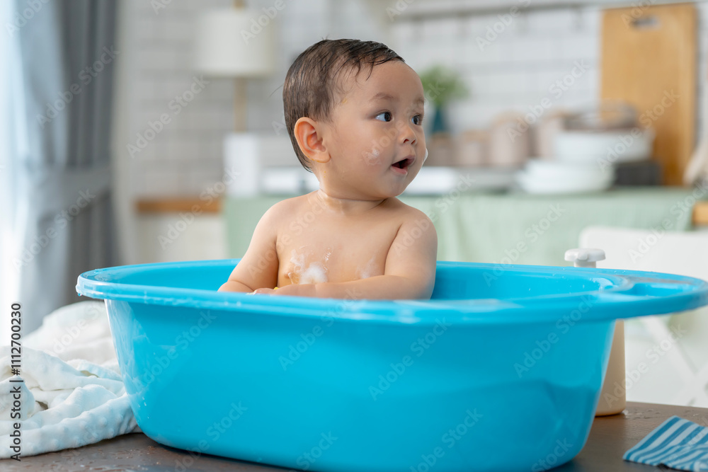 Asian baby taking a bath in a blue tub at home. Asian baby taking a bath in a blue tub at home.