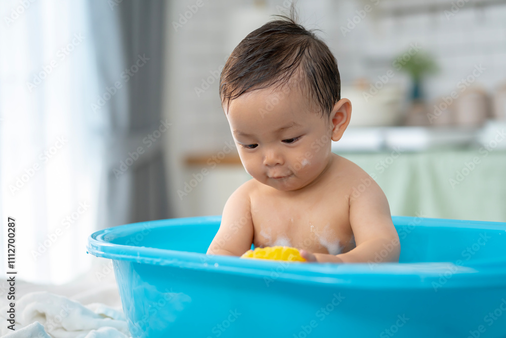 Asian baby taking a bath in a blue tub at home. Asian baby taking a bath in a blue tub at home.
